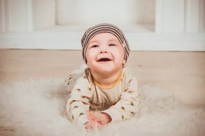 एक छोटा प्यारा बेबी जमीन पर लेटा हुआ मुस्कुरा रहा है
