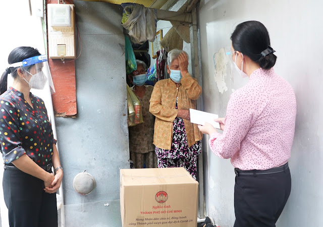 Đồng chí Triệu Lệ Khánh, Phó Bí thư Thường trực Quận ủy trao quà và tiền cho các hộ dân hoàn cảnh khó khăn. (Ảnh: P. Uyên)