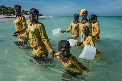 students in yellow fill lenghth cloting walk to shore after a swimming lesson, Muyuni Beach, Zanzibar, 2016