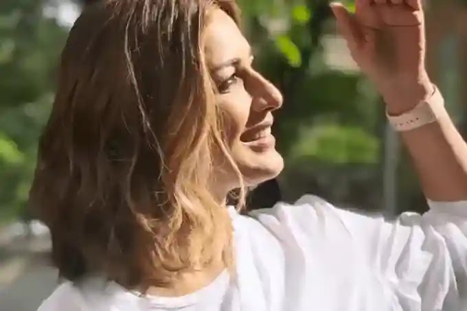 sonali bendre looking to upper side her one hand reached to protect eyes from the sun