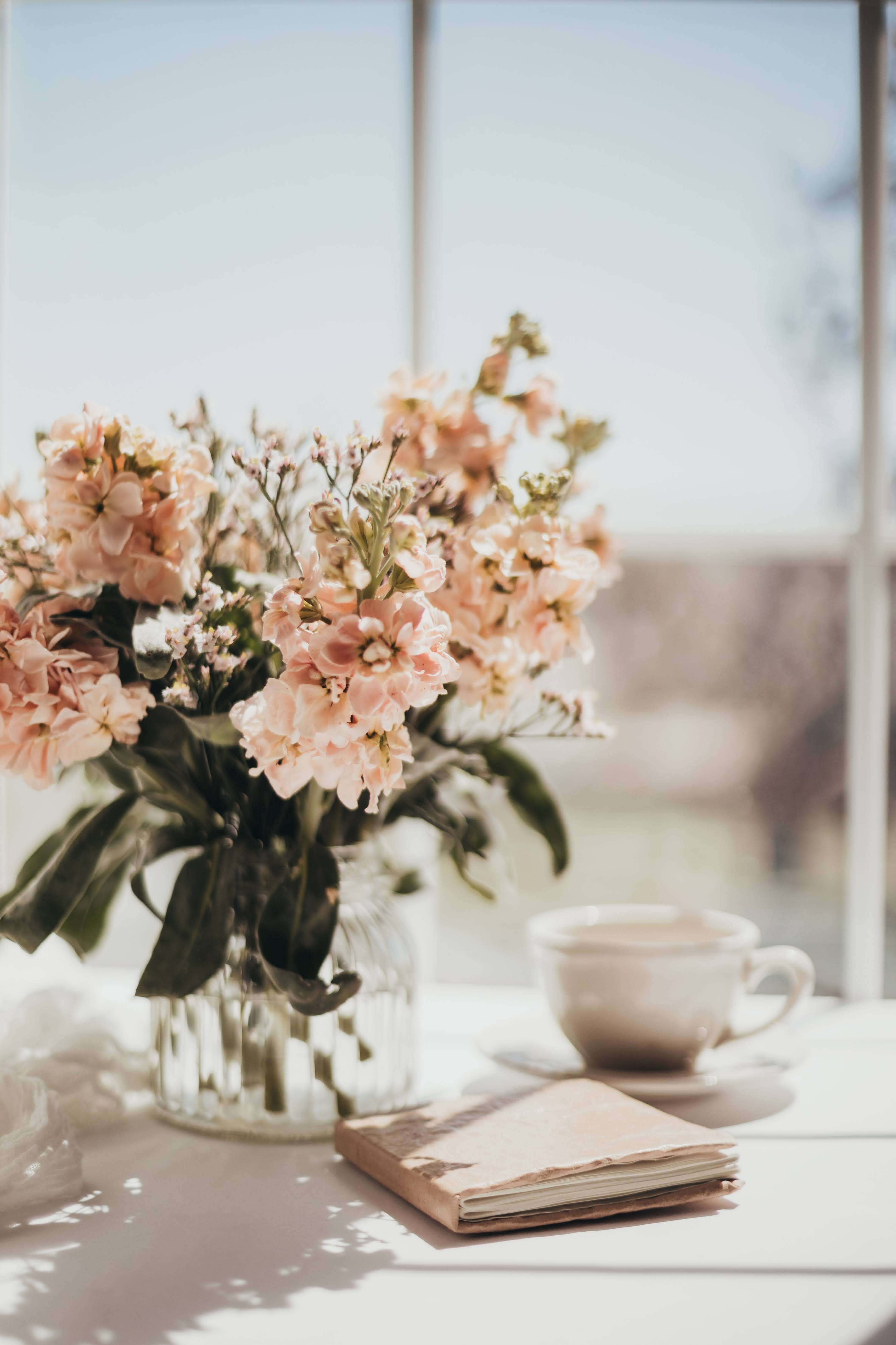 White and Pink Flowers in Glass Vase with White Ceramic Teacup and Journal | Photo by Sixteen Miles Out via Unsplash