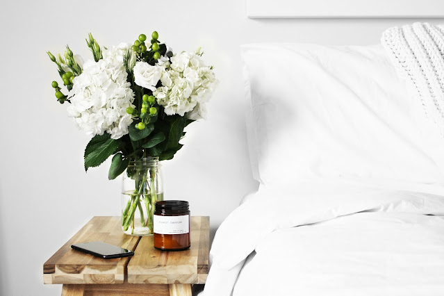 vase of flowers beside a bed