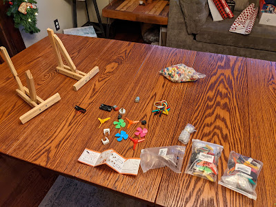 On a large table, the two trusses and an open bag of small parts: motors, switches, plastic fan blades that fit to the motors, battery cases, and a large assortment of wires.