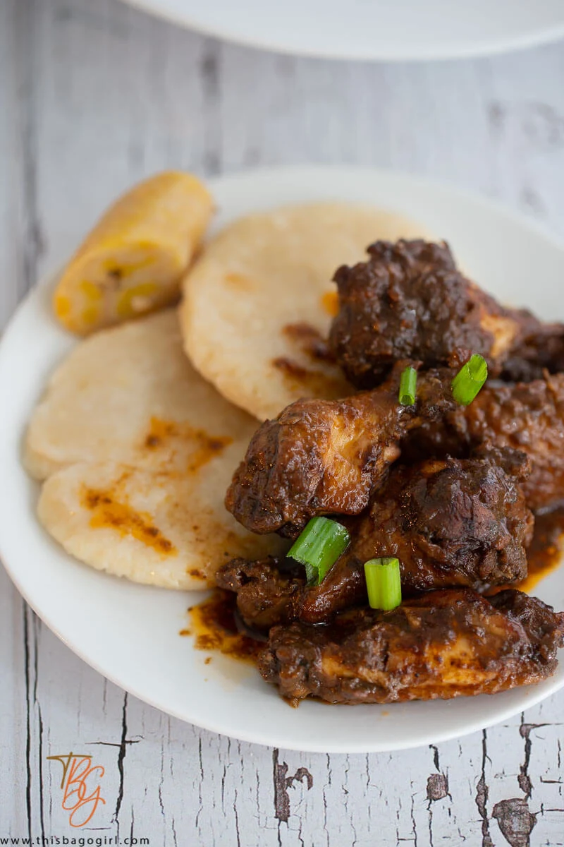 A close up of chicken wings in a plate with two cassava dumplings and boiled plantain.