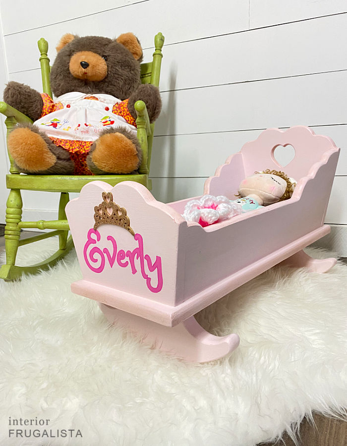 A vintage wooden doll cradle makeover painted a pretty pink and personalized with hand-painted child's name and DIY bedding fit for a little princess.