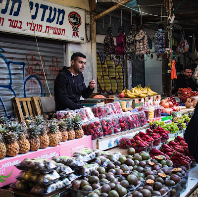 Man selling fruits in Israeli shuk (Credit: bec s./Unsplash)