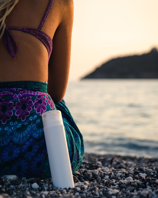 Woman on beach with bottle of sunscreen:Photo by Antonio Gabola on Unsplash
