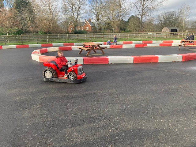 Little boy riding a motorised car around a track