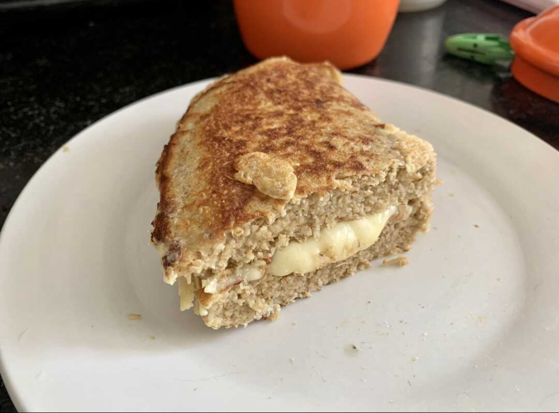 Foto de porção de panqueca fit recheada com queijo em prato branco em cima de superfície de mármore preto