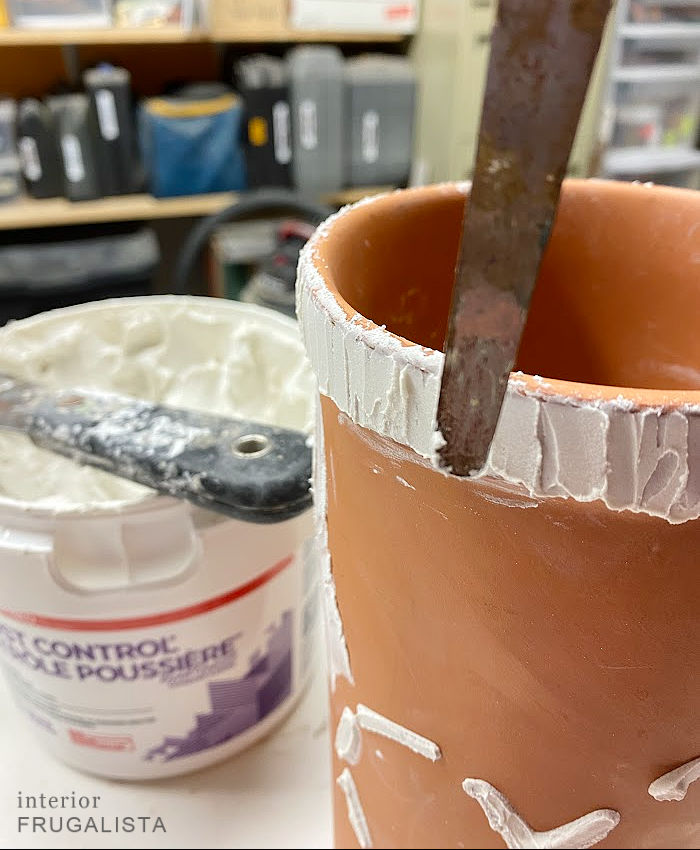 Using drywall spackle to create a handcrafted raised rim along a repurposed terracotta wine cooler.