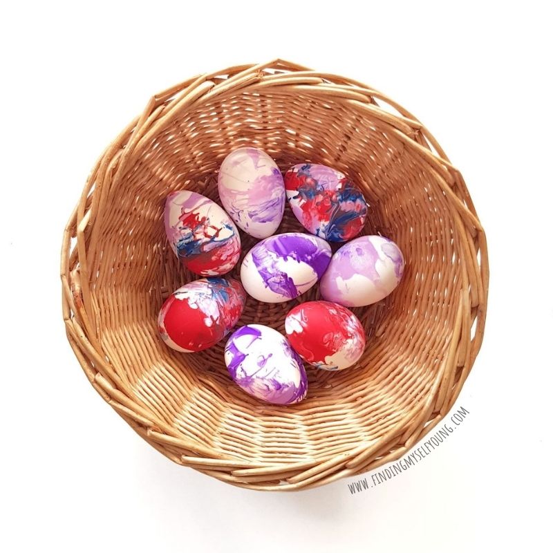 spin art decorated easter eggs on display in a basket