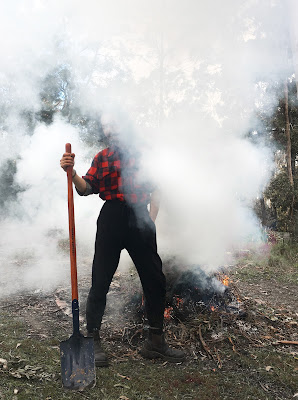 Man in plaid shirt emerging from the smoke of a burning tree