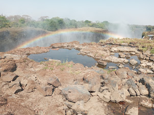 Rainbow formation over mist of Main fall of Victoria Falls .