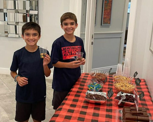 two boys holding cups of trail mix by table