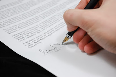 A hand signing a contract