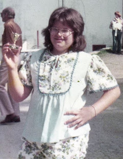 Author Karol Ruth Silverstein pictured as a chubby 9 year old in a 70s style outfit, holding up a tiny trophy.