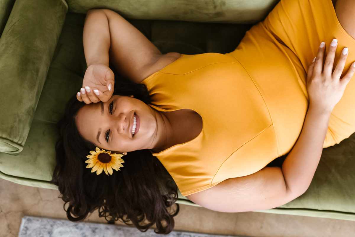 a beautiful curvy woman in posing on a sofa in a yellow dress