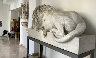 a statue of a lion lying in wait in front of a table for a talk