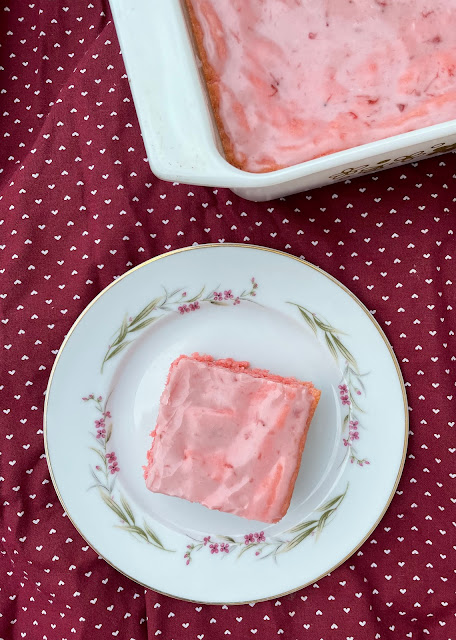 Baked glazed strawberry cake mix brownies with a square on a serving plate.