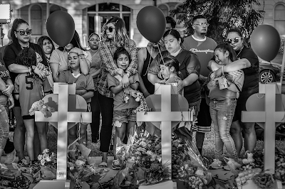 black and white photo of Local children and their parents react to a makeshift memorial in downtown Uvalde, nearby Robb Elementary School, on May 26