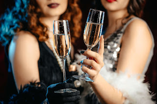 Two women with feather boas toasting champagne.