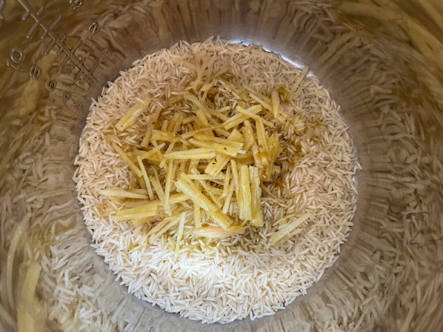 Adding the ginger and dissolved stock cubes to the rice.