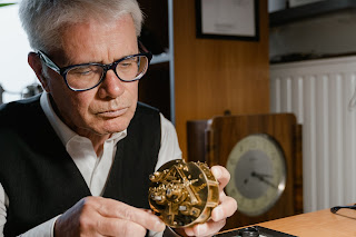An elderly man working on a clock.