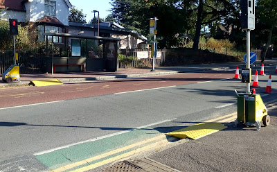 Photo shows a temporary pelican crossing with mobile pedestrian signals and portable ramps from the pavement to the road.