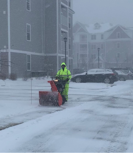 A member of the maintenance team pushing a snow blower at The Heights Amesbury