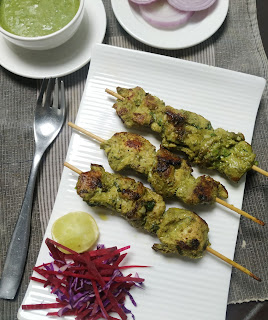 Serving three pahadi kabab sticks with green chutney and onion slices