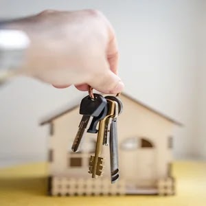 Foto imagem de um molho de chaves de imóveis locado em primeiro planto e ao fundo o desenho de uma casa ilustrando isenção de multa na transferência de funcionário
