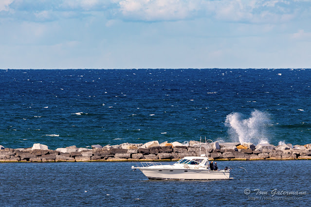 A boat in the harbor, with the breakwater behind the boat