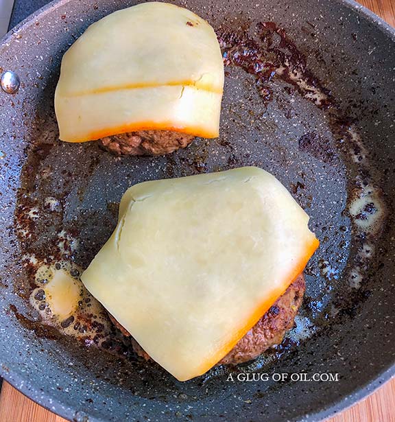Burgers in a frying pan with cheese melting