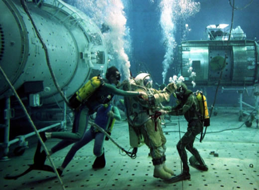 O instrutor de testes russo Oleg Pushkar é auxiliado por mergulhadores durante testes subaquáticos em uma réplica da estação espacial Mir danificada em 4 de julho de 1997.