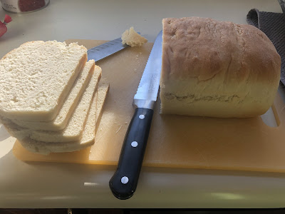 A pic of my first batch of homemade bread sitting on the countertop to the left of the sink half of it cut.