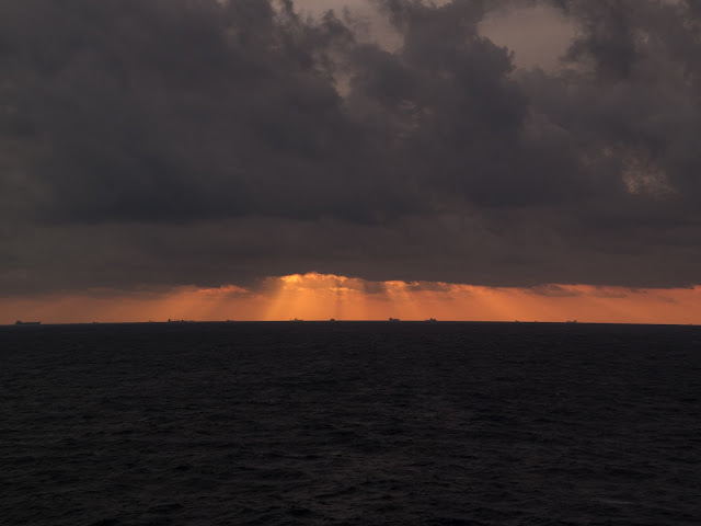 Pink sunlight rays cast from a dark cloud on the Mediterranean Sea.