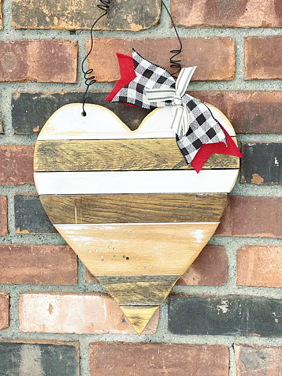 wooden heart with bow on brick wall