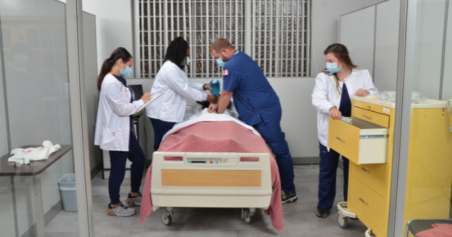 This image shows 4 nurses in a medical setting working on a mannequin patient.