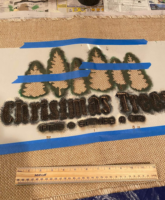 Photo of a jute rug being stenciled with a Christmas Trees stencil.