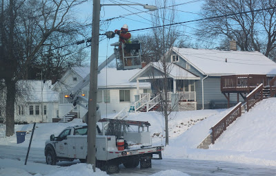 winter scene of bucket truck with man working on overhead cable-internet wires