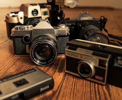 Table with five different old film cameras on it