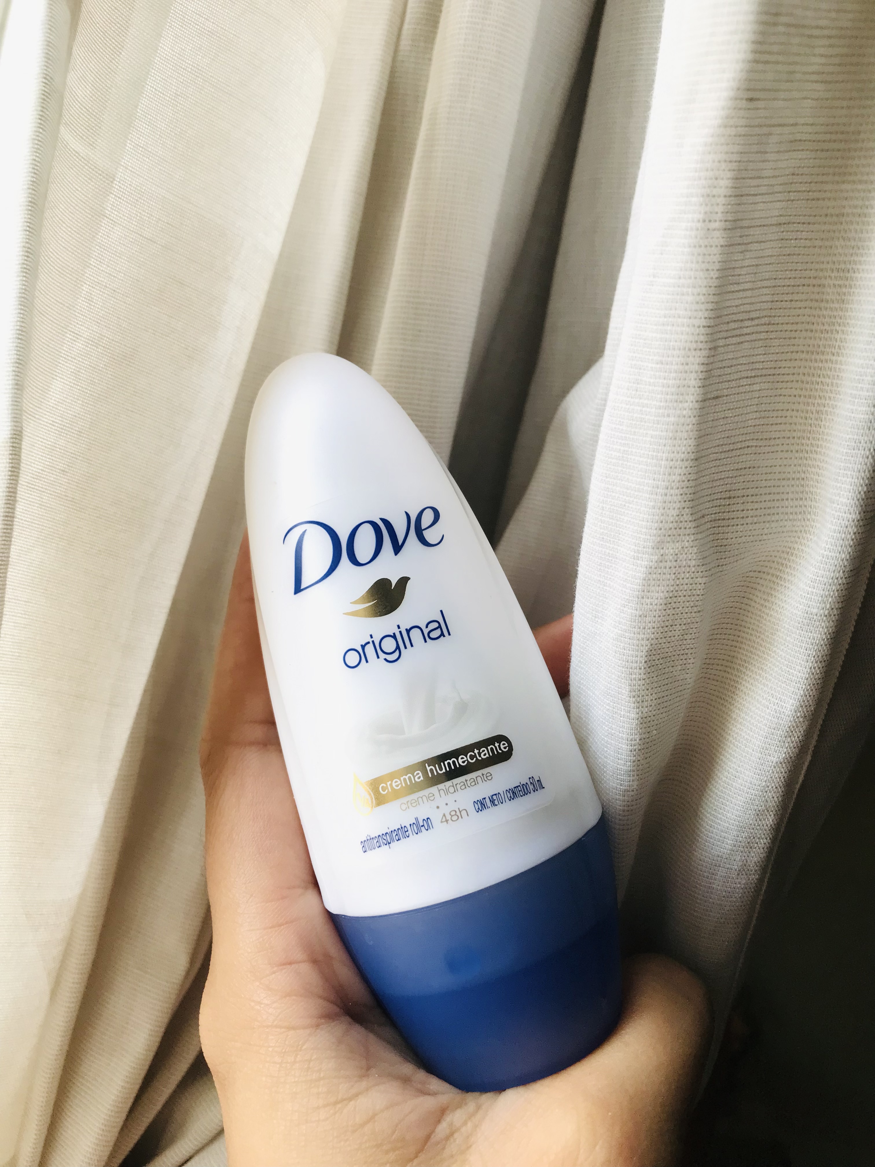 imagen de mano osteniendo envase ovalado blanco con tapa azul