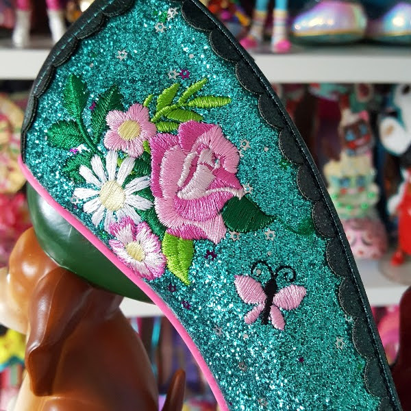 floral embroidery on side of green glitter shoe up close