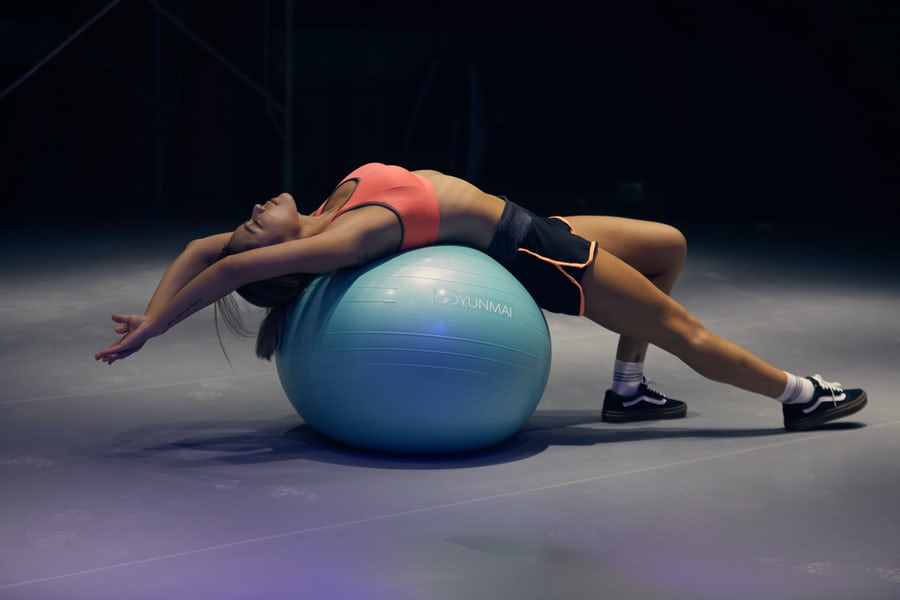 A fitness woman using a training ball to pose in yoga position to lose weight