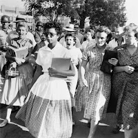 A black schoolgirl walks to class as her white classmates scream angerly behind her