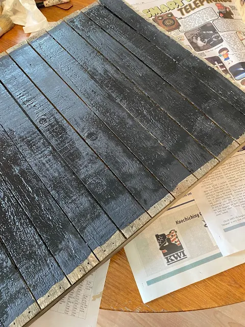 Photo of a thrifted slatted sign being painted with black chalk paint.