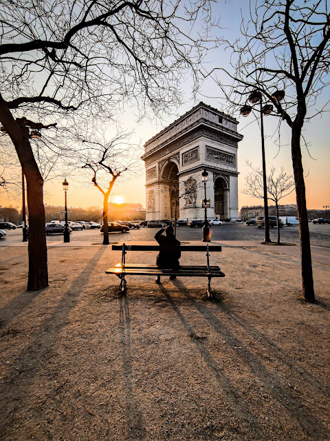 Person sitting on bench looking towards the Arc de Triophe in Paris