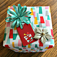 colorful gift wrapped in retro-style paper, handmade paper bow, and quilled tree ornament