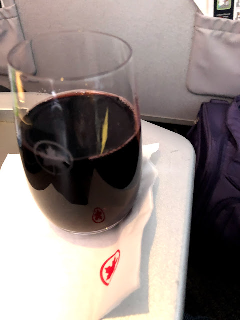 A glass (real glass) of red wine on a business class armrest