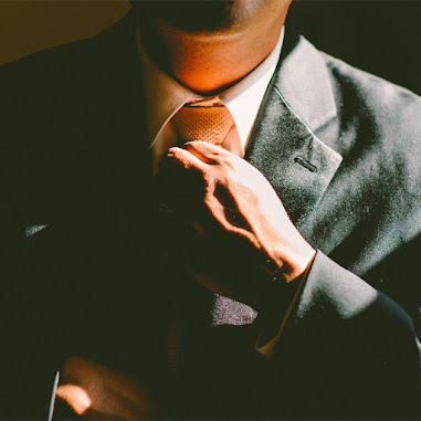 homme negociateur en costume gris avec une cravate orange qui reajuste sa cravate